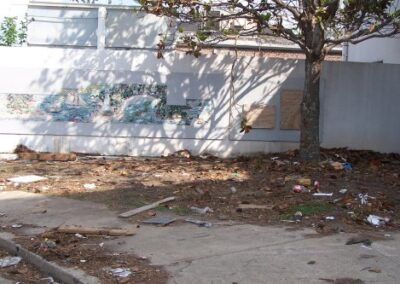 A courtyard area beside the library shows scattered debris, fallen leaves, and damaged landscaping. A wall mural is partially visible beneath boarded‑up windows.