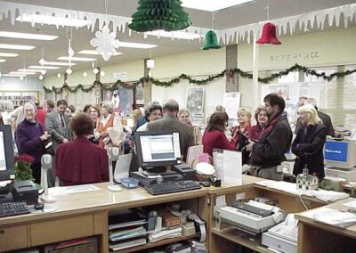 A decorated sheet cake features a drawing of a tree growing from an open book with the words “Growing With A Growing Community” written beside it. The cake is bordered with colorful icing flowers.
